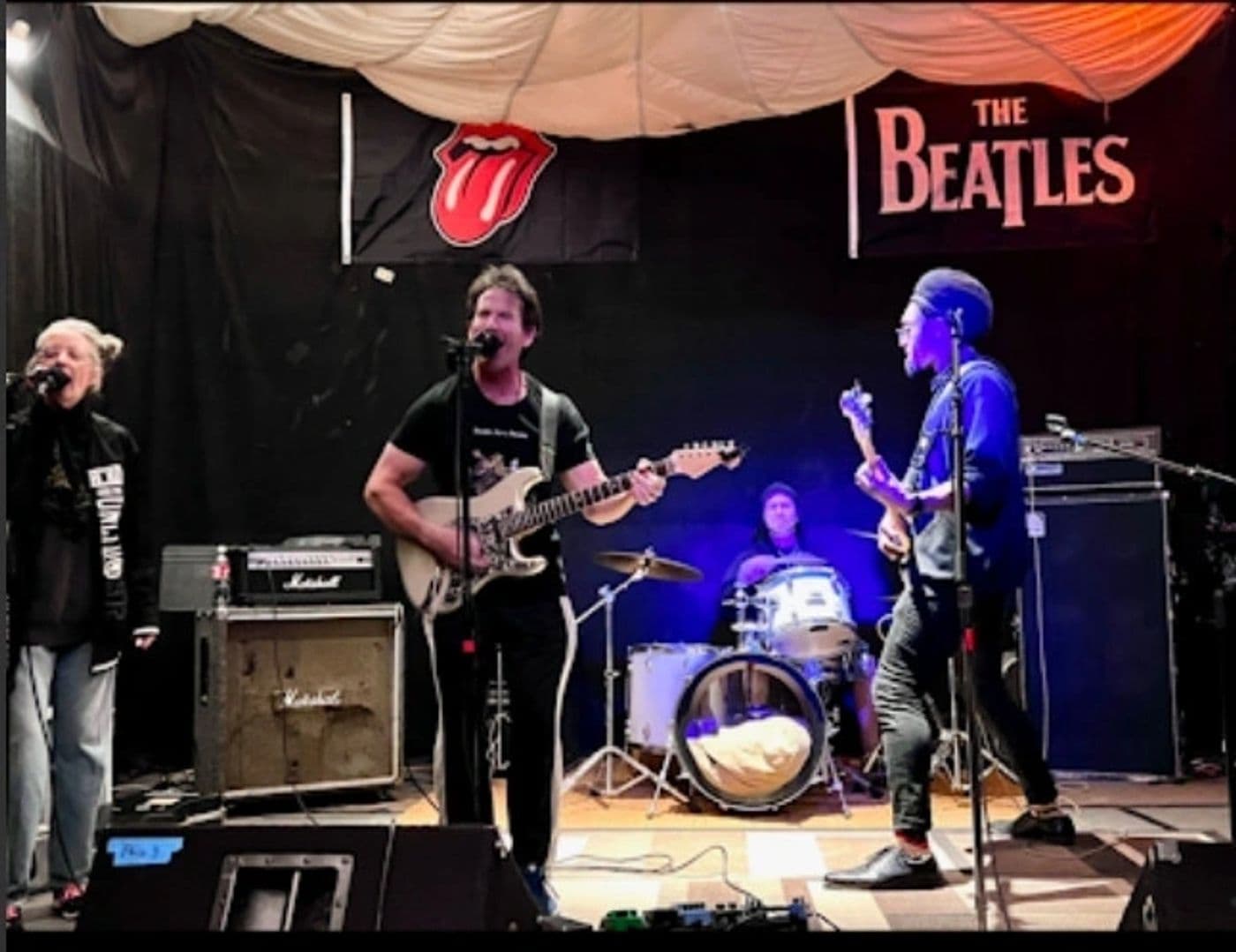 Clydescope playing a full set on stage beneath Rolling Stones and Beatles banners