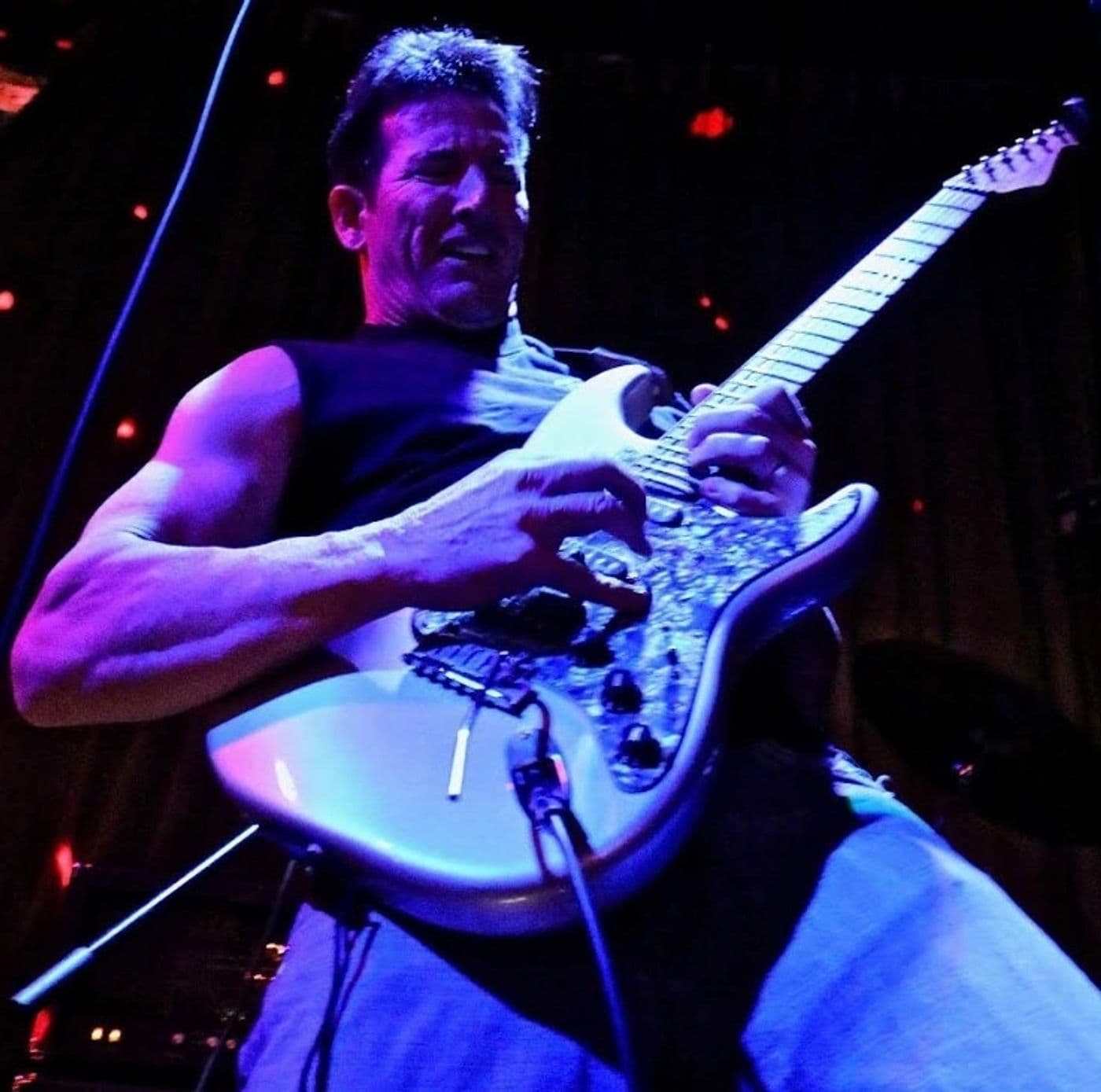 Clydescope guitarist lit in blue stage light, deep into a solo