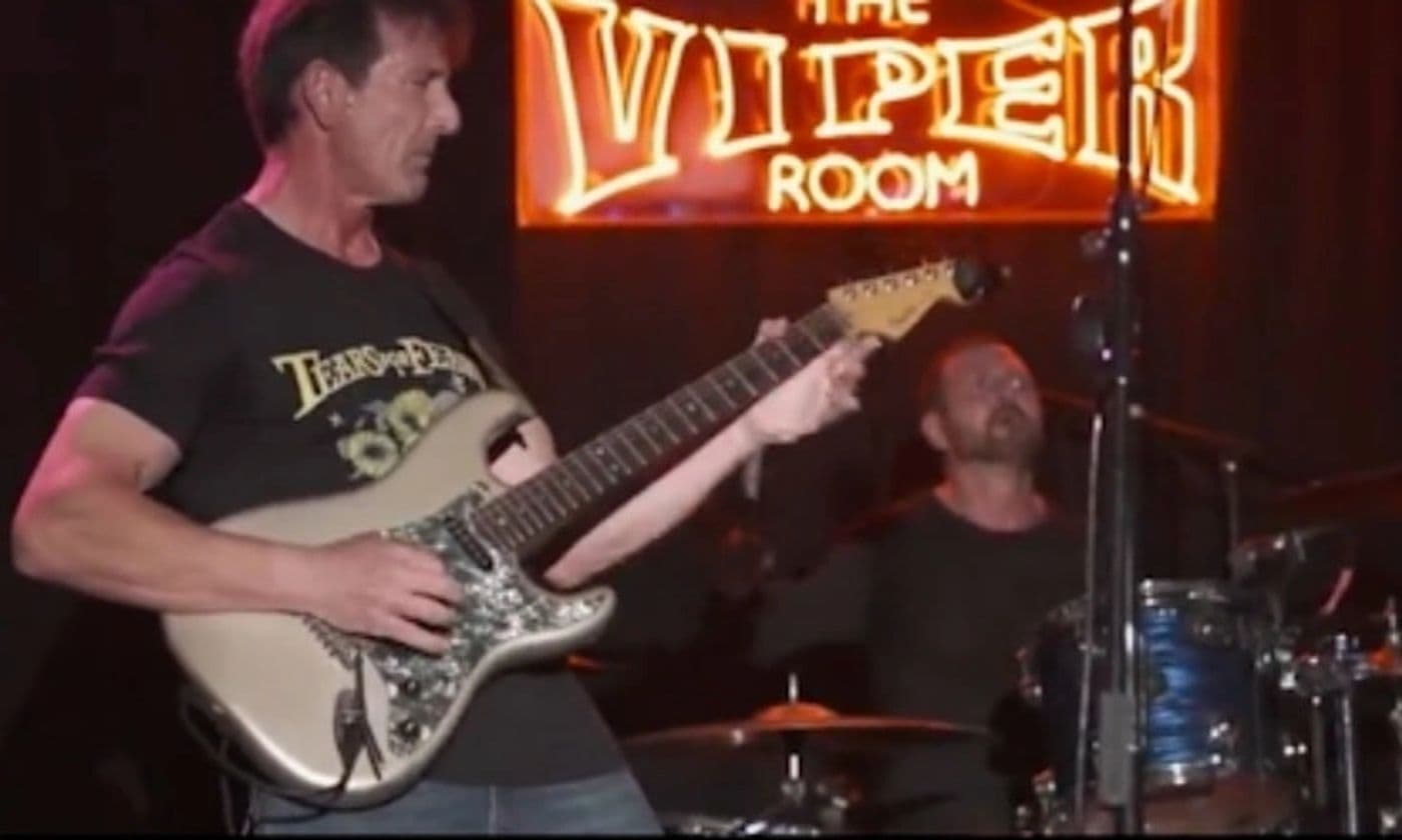 Guitarist and drummer playing together in front of the Viper Room neon sign