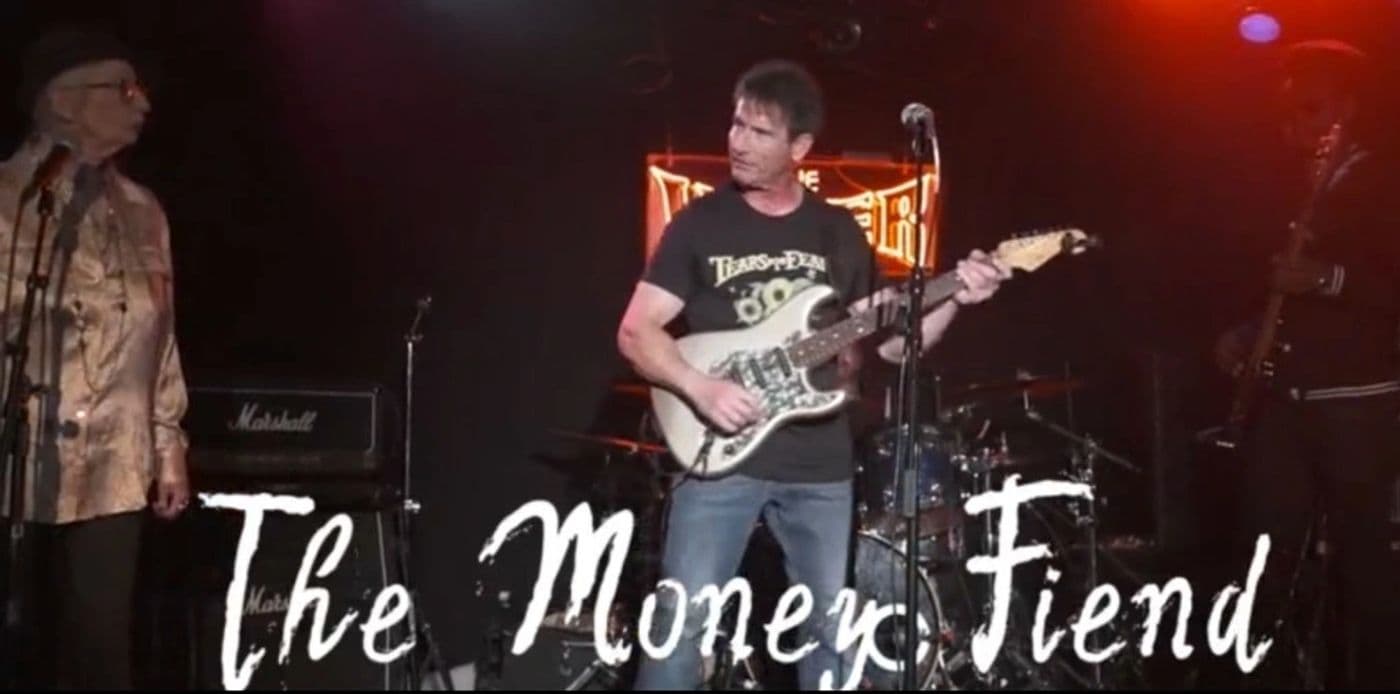 Live still from The Money Fiend, guitarist and singer on stage