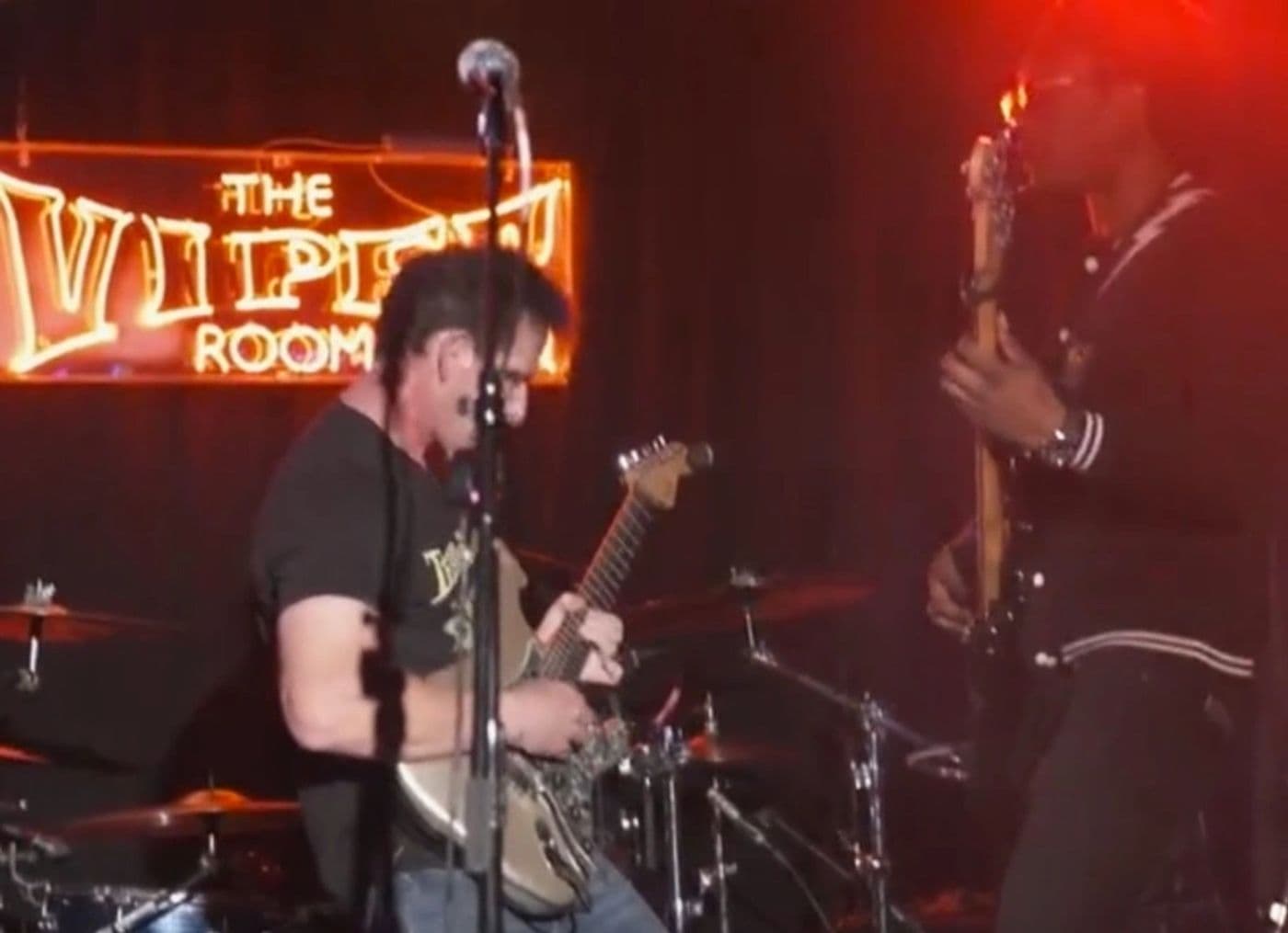 Guitarist playing directly beneath the glowing Viper Room neon sign