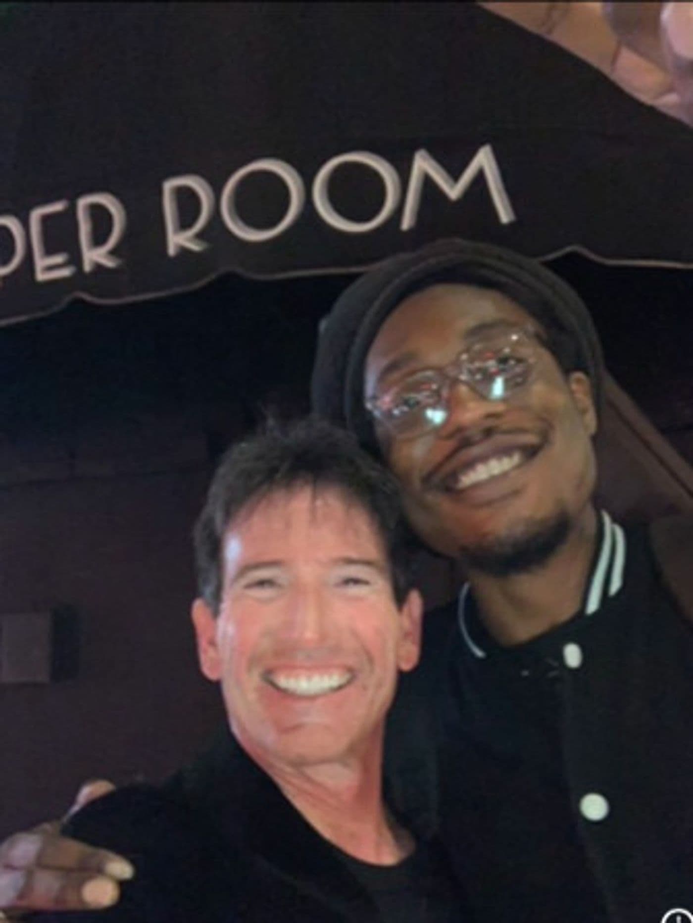 Two friends smiling for a photo outside the Viper Room at night